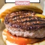 A grilled burger with mustard, ketchup, and tomato.