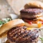 Two grilled backyard burgers with tomato.