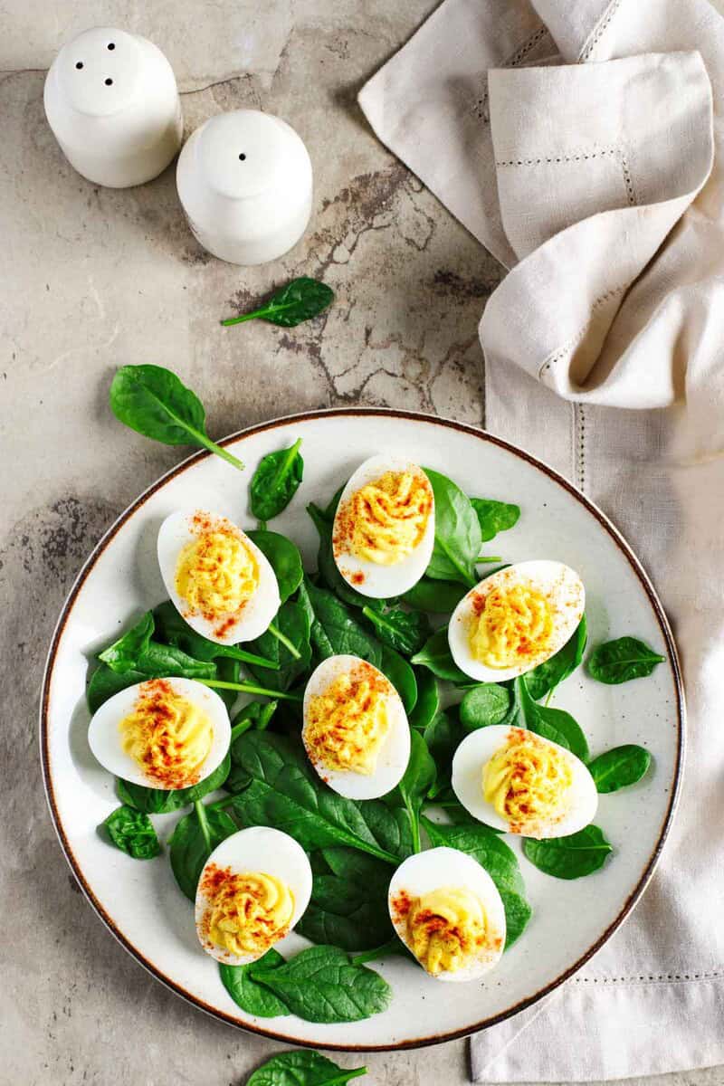 Classic deviled eggs on a plate, cloth napkin, and salt and pepper shakers.