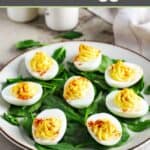 Classic deviled eggs and fresh spinach leaves on a plate.