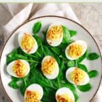 Classic deviled eggs on a bed of fresh spinach leaves on a plate.