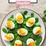 A plate of classic deviled eggs on a bed of fresh spinach.