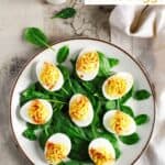 Classic deviled eggs on top of spinach on a plate.