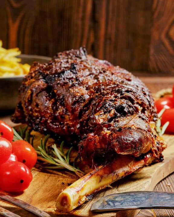 Oven roasted Indian style kashmiri leg of lamb on a cutting board.