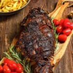 Oven roasted Indian style kashmiri leg of lamb on a wood cutting board.