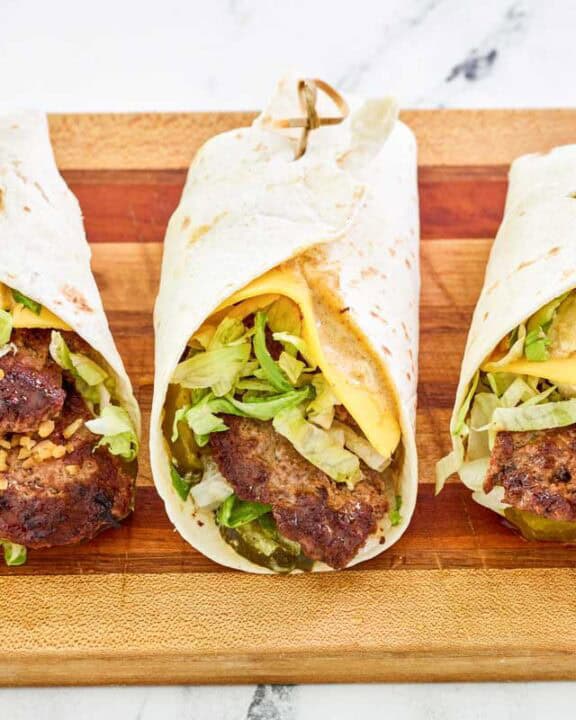 Three copycat McDonald's big mac wraps on a wood cutting board.
