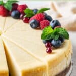 Slices of New York style cheesecake topped with berries and mint leaves.
