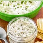 Homemade dry ranch dressing mix in a mason jar and ranch dip behind it.