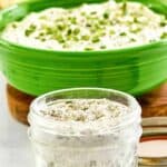 Homemade dry ranch dressing mix in a mason jar and ranch dip behind it.