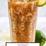 Homemade sonic dirty diet coke in a glass and a lime behind it.