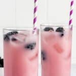 Two homemade Starbucks violet drinks with blueberries on coasters.