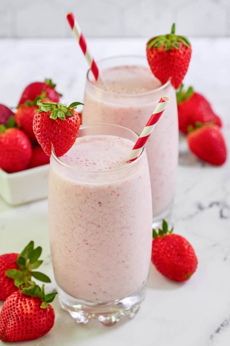 Copycat strawberry julius in two glasses and fresh strawberries around them.
