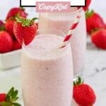Homemade strawberry julius with a straw and strawberries around it.