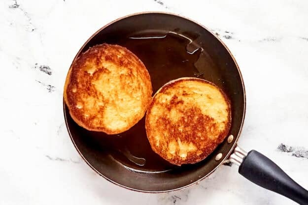 Two butter toasted hamburger buns in a skillet.
