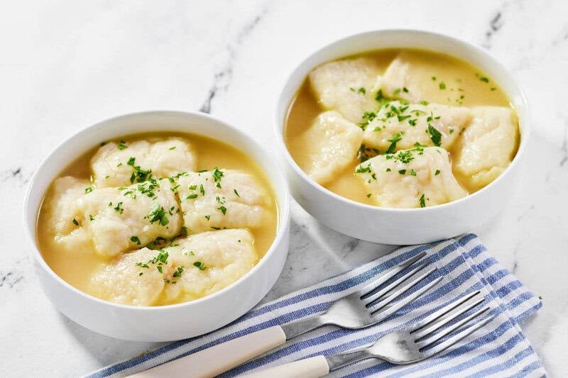 Copycat cracker barrel dumplings in two bowls and two forks on a cloth napkin.
