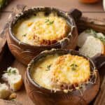 Bowls of homemade classic French onion soup on a wood tray.