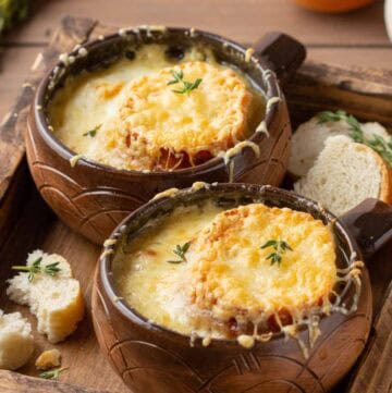 Bowls of homemade classic French onion soup on a wood tray.