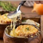 Homemade French onion soup on a spoon and a bowl.