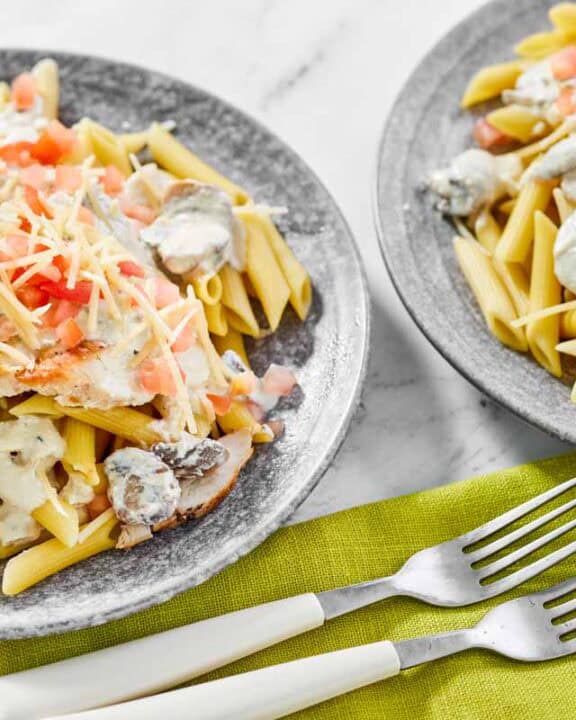 Copycat Johnny Carino's chicken penne gorgonzola on two plates and two forks.