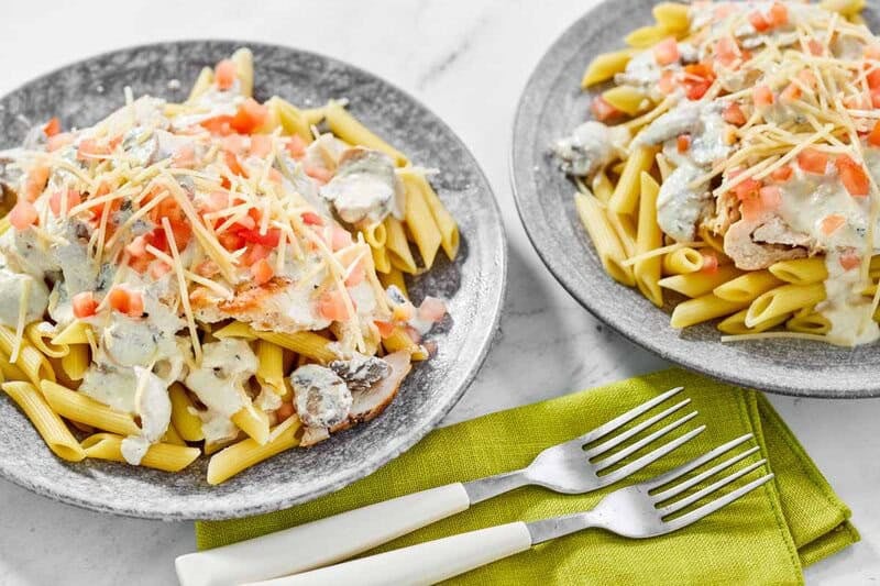 Copycat Johnny Carino's chicken penne gorgonzola on two plates and two forks.