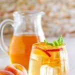 Homemade Olive Garden peach iced tea in a pitcher and wine glass.