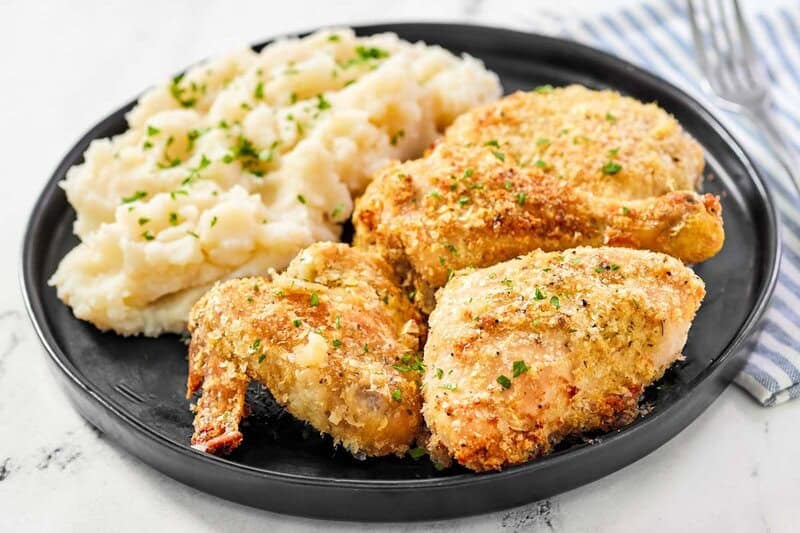A few pieces of potato flake chicken and mashed potatoes on a plate.