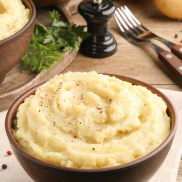 Homemade simple mashed potatoes, forks, and a pepper grinder.