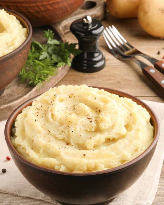 Homemade simple mashed potatoes, forks, and a pepper grinder.
