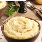 Simple homemade mashed potatoes in a bowl on top of a cloth napkin.
