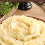 A bowl of homemade mashed potatoes with black pepper sprinkled on top.