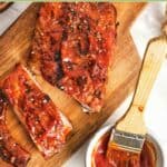 Homemade St. Louis style barbecue sauce on baby back ribs and in a small cup.