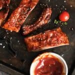 Homemade St. Louis style BBQ sauce in a small cup and on pork ribs.