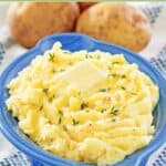 Homemade yukon gold mashed potatoes and two potatoes behind it.