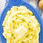 Yukon gold mashed potatoes topped with butter in a serving dish.