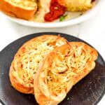 Slices of copycat Marie Callender's garlic toast on a plate and with lasagna.