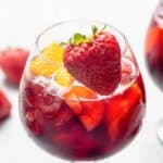 A glass of homemade Olive Garden sangria with a strawberry on the rim.