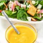 Homemade Simon and Seafort's mustard dressing in a small glass bowl and a salad.