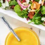 Homemade Simon and Seafort's mustard dressing in a small bowl next to a salad.