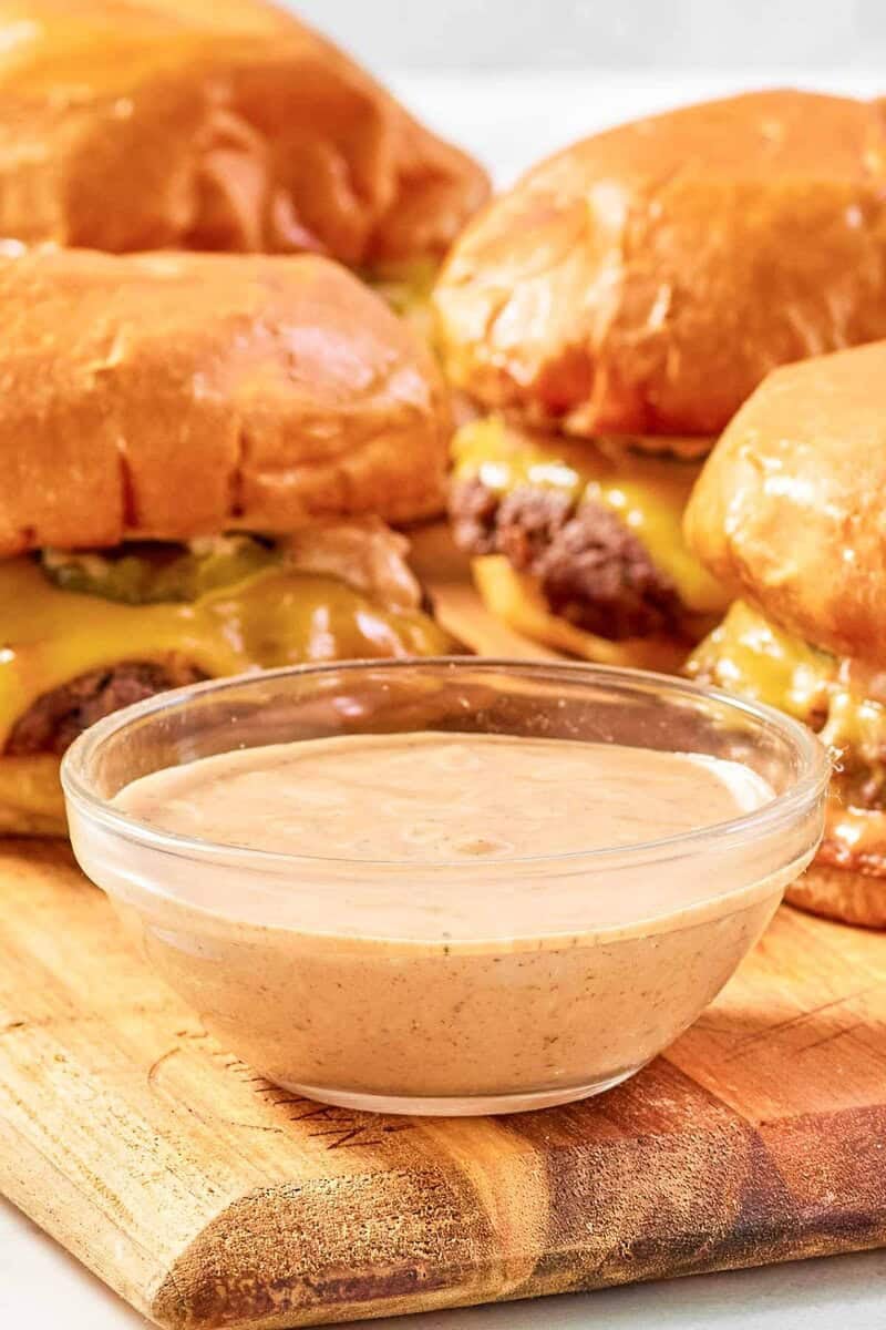 Copycat Sonic smasher sauce in a bowl and smasher burgers behind it.