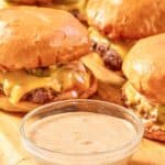 Homemade Sonic smasher sauce in a condiment bowl and burgers behind it.