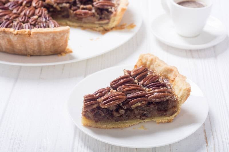 Copycat Taste of Texas pecan pie slice on a plate and the pie behind it.