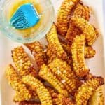 A platter of air fryer corn ribs and melted butter in a small glass bowl.