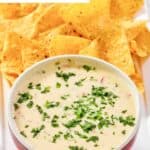 A bowl of homemade Applebee's queso blanco dip and chips on a platter.