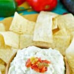 A bowl of copycat Casa Ole green sauce and tortilla chips around it.