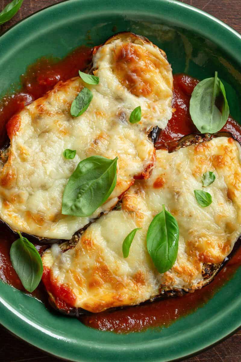 Homemade eggplant parmesan garnished with fresh basil leaves.