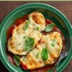 Eggplant parmesan on a plate garnished with basil leaves.