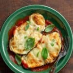 Homemade eggplant parmesan and a fork on a plate.
