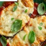 Homemade eggplant parmesan on a plate garnished with basil.