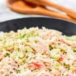 A bowl of homemade Golden Corral seafood salad and salad tongs behind it.