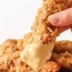 Dipping a chicken tender into honey mustard sauce.